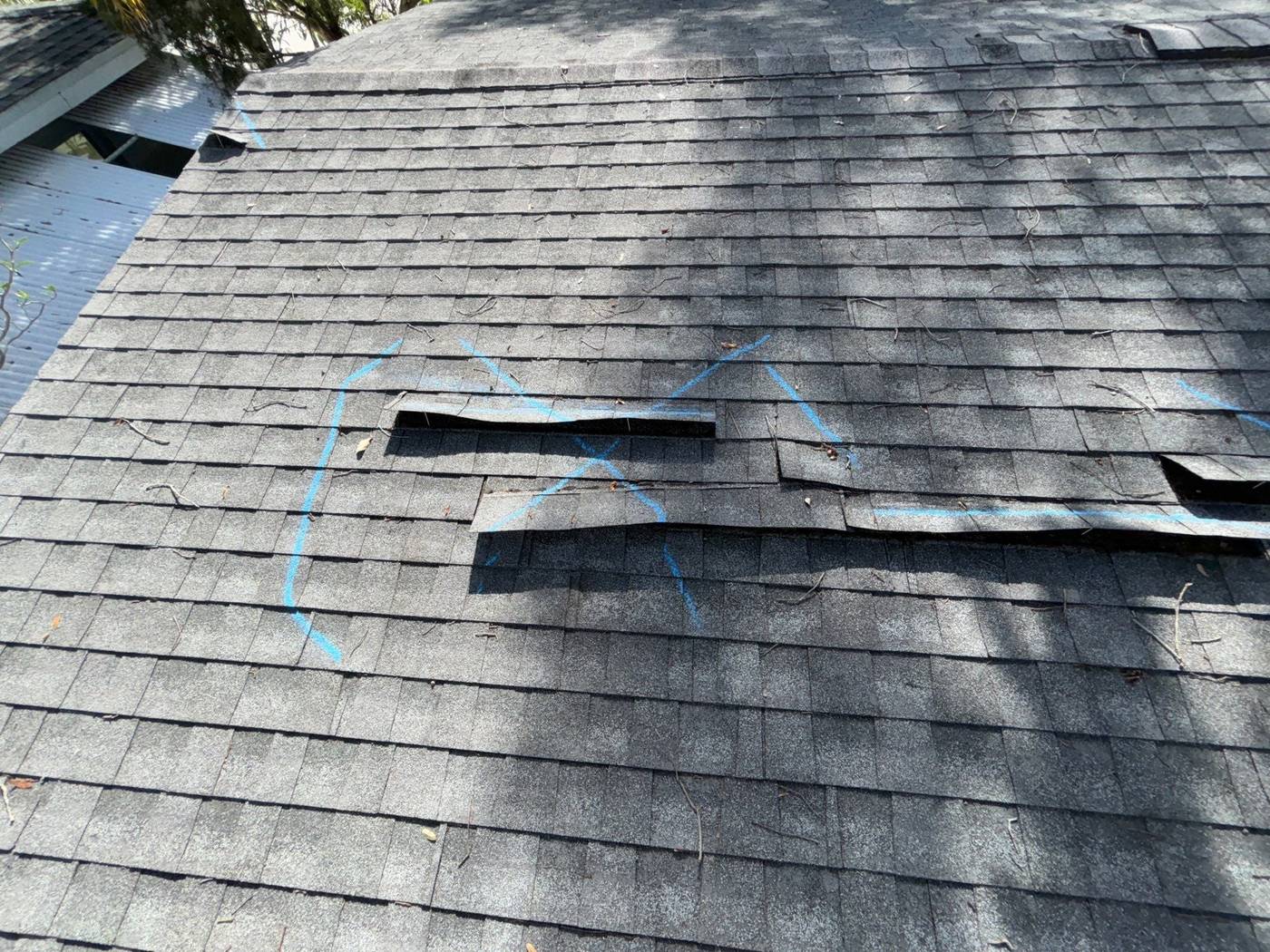 Creased roof shingles marked with chalk during an inspection