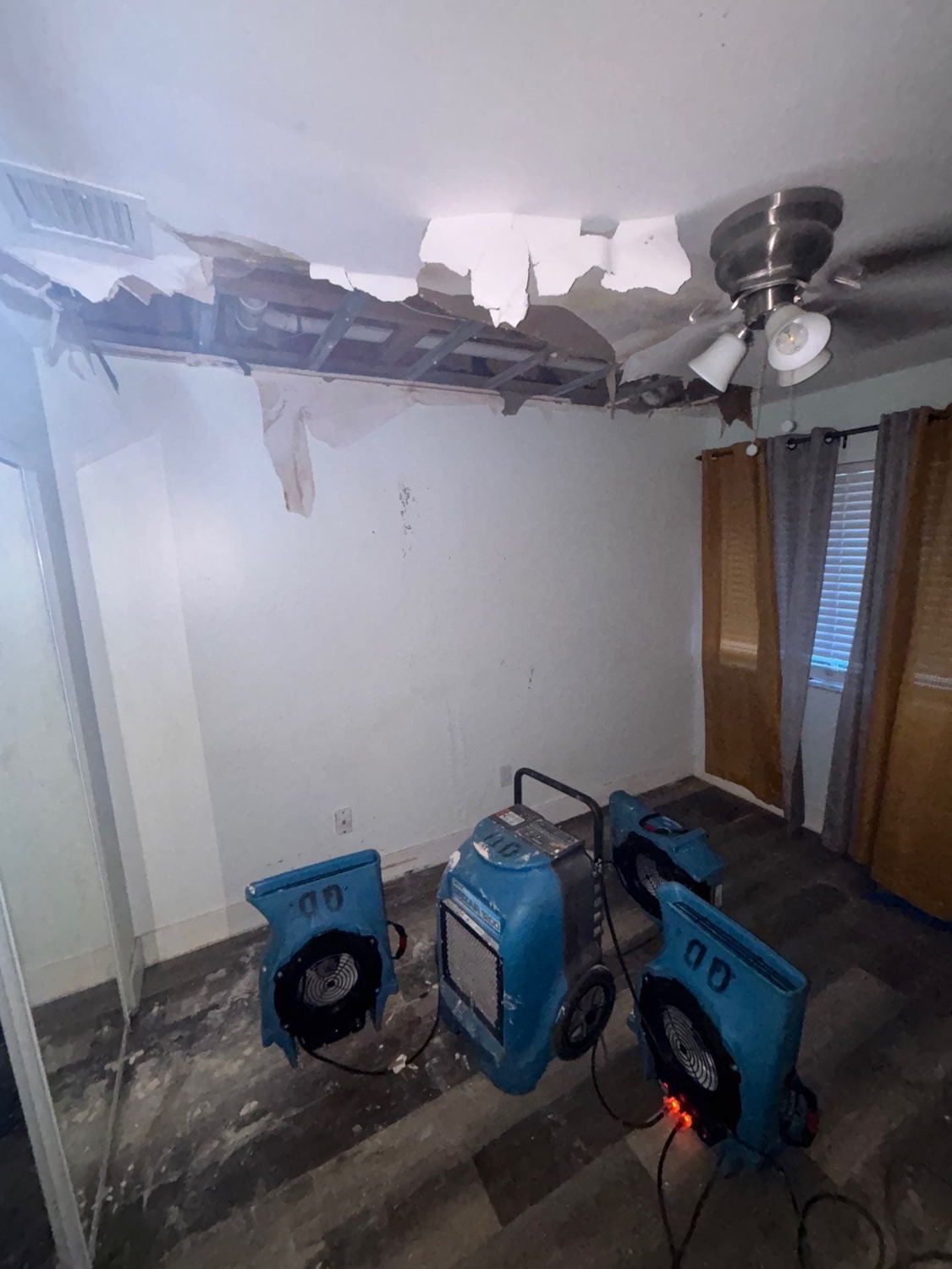 Collapsed ceiling section with three air movers running beneath it